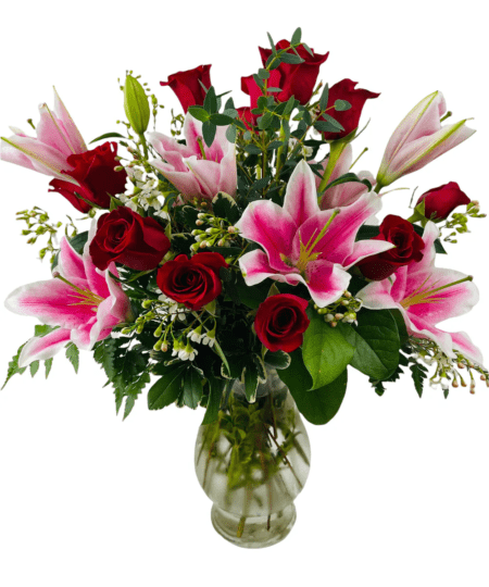 A dozen beautiful long stemmed red roses are arranged in a glass vase with Stargazer lilies, premium accent flower, and mixed greens. 